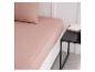 Un drap housse rose sur un lit, avec une table de chevet à côté.