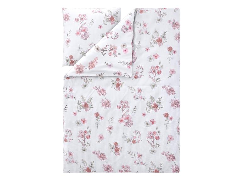 Parure de lit avec housse de couette et taie d'oreiller à motif floral rose sur fond blanc.