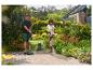 Un couple nettoie une allée de jardin pavée avec un nettoyeur haute pression et une brosse à désherber.