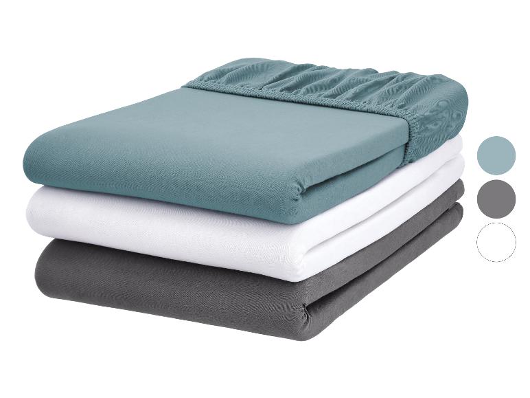 Draps-housses empilés en bleu-vert, blanc et gris avec des échantillons de couleur.
