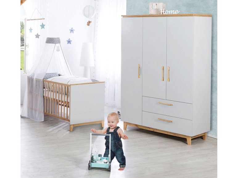 Chambre de bébé avec berceau blanc, armoire et un enfant poussant un trotteur.