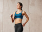 Une femme porte un soutien-gorge de sport bleu et un legging noir pendant l'exercice.