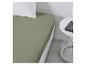 Un drap-housse vert sur un lit avec un oreiller blanc.