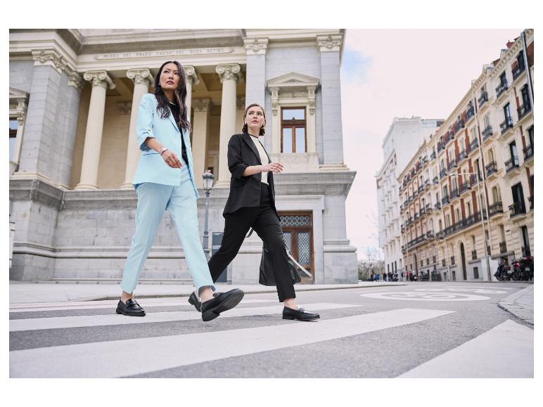 Deux femmes en costumes élégants traversent un passage piéton.
