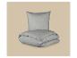 Oreiller gris et couette pliée sur fond beige.