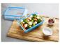 Boîte alimentaire bleue avec salade de brocoli et patate douce à la feta, sel et poivre.
