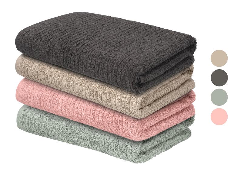 Une pile de quatre serviettes côtelées pliées en gris foncé, beige, rose et vert clair.