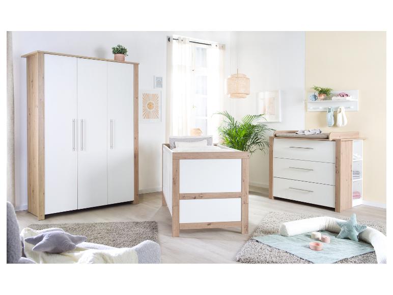 Chambre de bébé blanche et bois avec un lit à barreaux, une armoire et une table à langer.