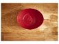 Un bol rouge sur une surface en bois.