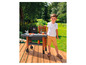 Un enfant joue avec un barbecue jouet Smoby sur une terrasse en bois.