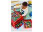 Un enfant joue avec des blocs LEGO colorés sur une boîte de rangement rouge.