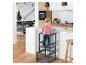 Enfant sur une tour d'apprentissage dans une cuisine moderne avec parquet et îlot blanc.