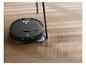 Robot aspirateur noir nettoyant un parquet en chevrons.