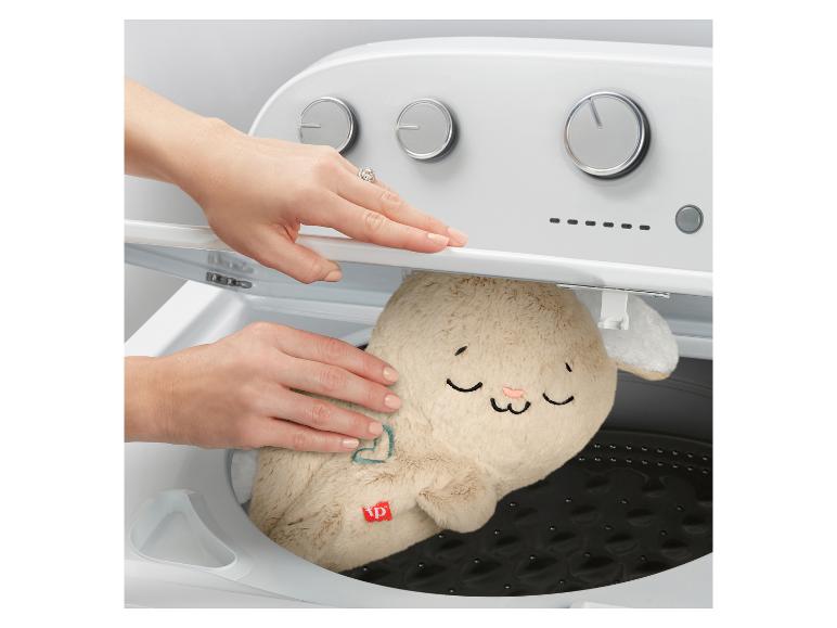 Une personne met une peluche en forme de lapin dans une machine à laver.