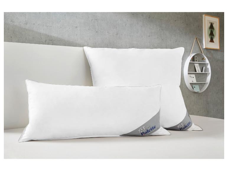 Deux oreillers Balette blancs avec logo 135 ans sur un lit.