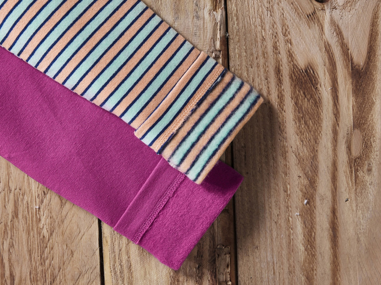 Un t-shirt rose et rayé sur un fond en bois.