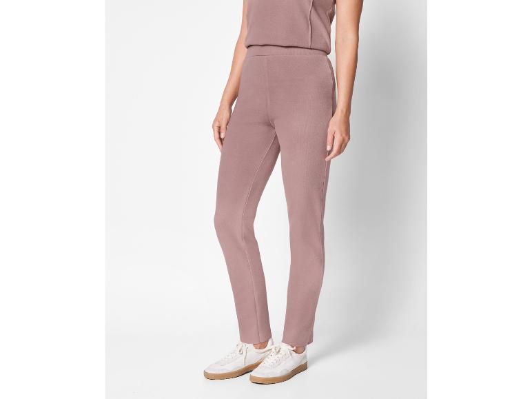 Une femme porte un pantalon rose et des baskets blanches.