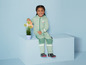Un enfant portant une combinaison verte et des bottes arrose une plante.
