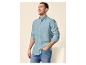 Homme en chemise en lin bleu clair et jean, souriant et regardant sur le côté.