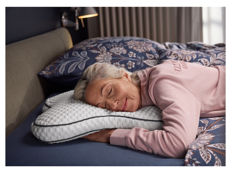 Une femme dort sur un oreiller à motif en nid d'abeille et une housse bleue.