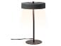 Lampe de table noire avec une base ronde et un abat-jour émettant une lumière chaude.