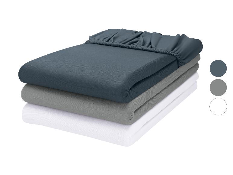Ensemble de trois draps-housses pliés en bleu foncé, gris et blanc avec des échantillons de couleur.