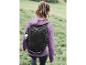 Une femme marche dans l'herbe avec un sac à dos Crivit noir.