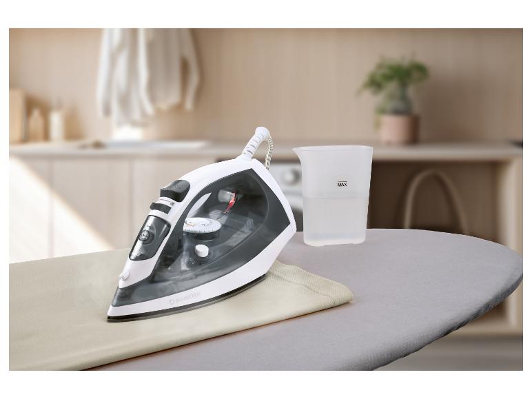 Fer à vapeur SilverCrest sur planche à repasser avec verre doseur d'eau, dans une buanderie.