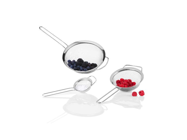 Trois tamis métalliques avec des framboises et des myrtilles.