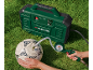 Compresseur d'air vert gonflant un ballon de football blanc sur l'herbe, avec une personne tenant le ballon et le manomètre.
