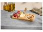 Planche à fromage en bois avec fromages, figues, raisins et couteaux sur un comptoir.