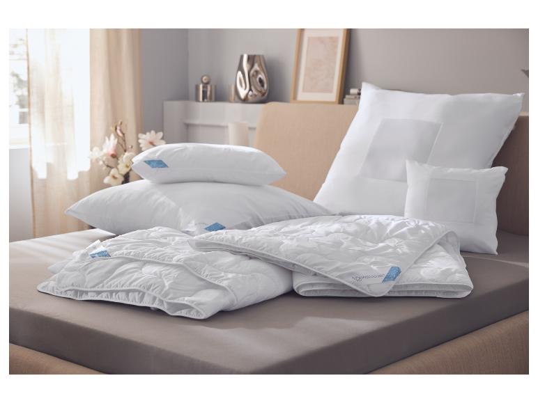 Oreillers et couettes blancs sur un lit, avec des étiquettes bleues Hydrocool.