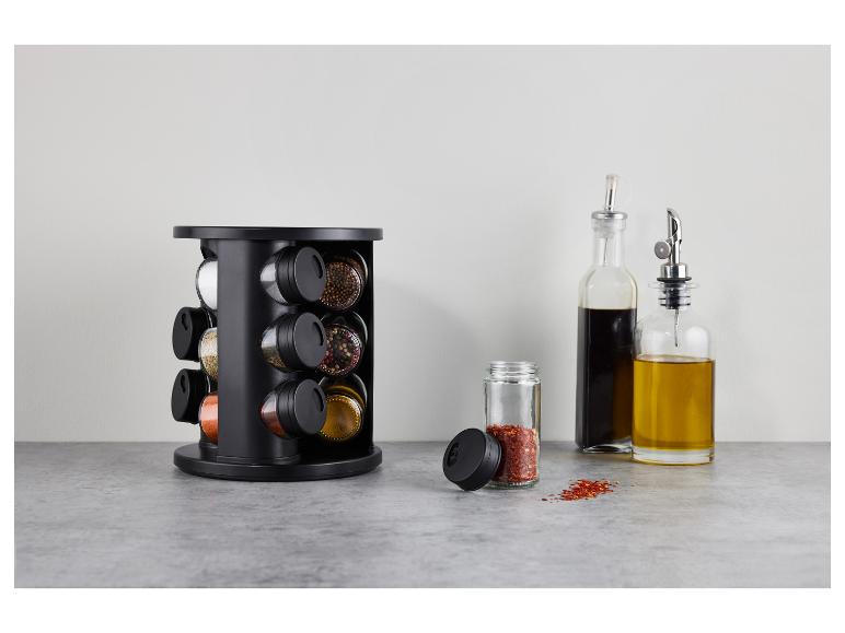 Étagère à épices noire avec diverses épices, bouteilles d'huile et de vinaigre sur un comptoir gris.