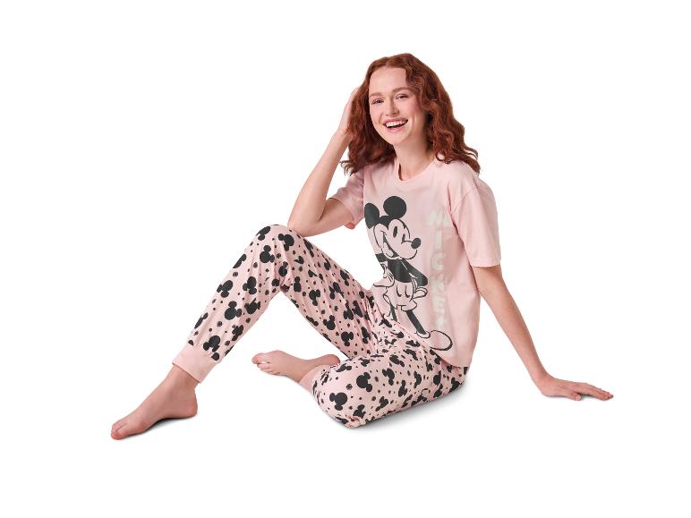 Femme en pyjama rose Mickey Mouse, assise et souriante.