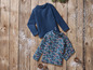 Deux chemises à manches longues bleues, l'une avec un motif floral, sur un fond en bois avec de la neige.