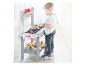 Enfant jouant avec un barbecue en bois jouet.