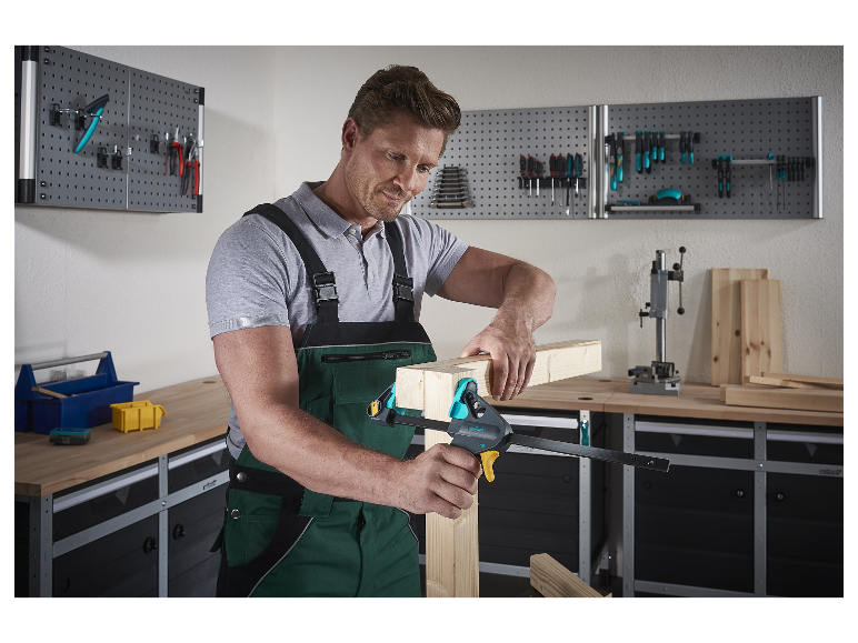 Un homme utilise une pince Wolfcraft pour assembler des pièces de bois dans son atelier.