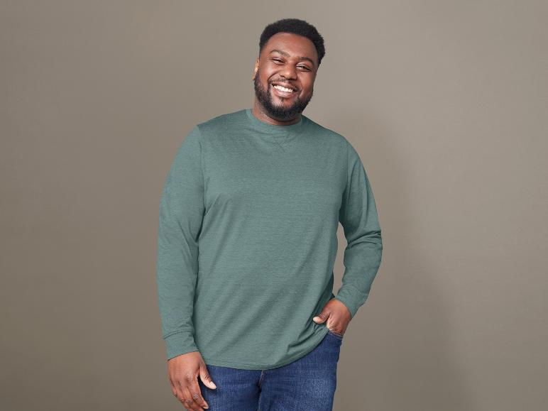 Un homme portant un t-shirt vert à manches longues et un jean.