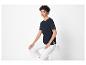 Une femme porte un t-shirt bleu marine avec de la dentelle et un pantalon blanc.