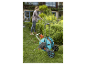 Arroseur et tuyau Gardena sur un chariot, dans un jardin.