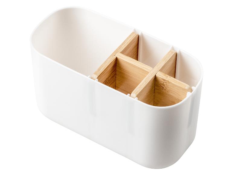 Un organiseur blanc pour couverts avec des inserts en bois.