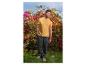 Homme en t-shirt jaune et pantalon vert foncé posant devant des fleurs.