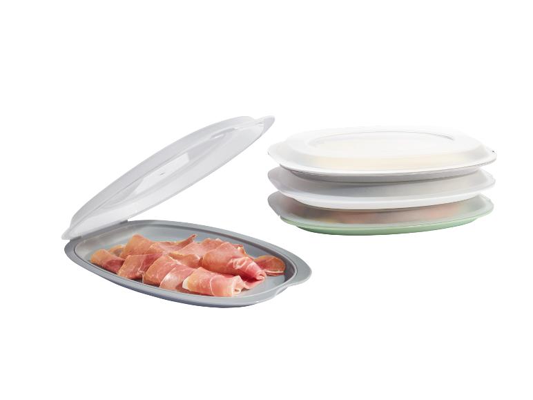 Plateaux empilables avec couvercles, un avec du jambon serrano.