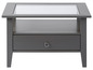 Table basse grise avec plateau en verre et tiroir.