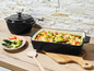 Un plat à gratin en fonte noir avec des légumes rôtis et une petite casserole en fonte.