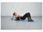 Une femme utilise un rouleau en mousse sur un tapis bleu pendant un entraînement.