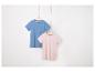 Deux t-shirts unis, bleu et rose pâle, suspendus à des cintres.