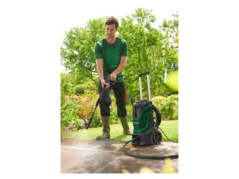 Homme nettoyant une terrasse avec un nettoyeur haute pression dans un jardin.