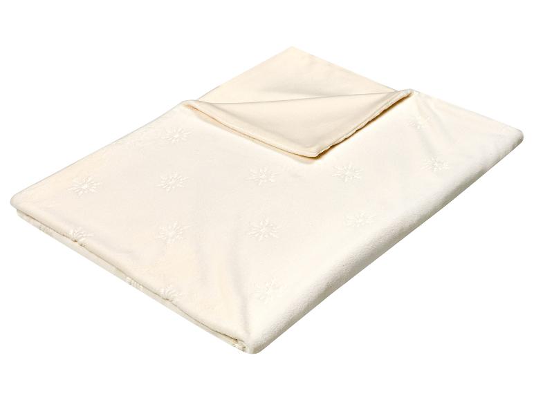 Couverture crème avec motif flocon de neige, pliée et prête à l'emploi.