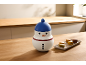 Récipient en forme de bonhomme de neige et macarons sur un comptoir en bois dans la cuisine.